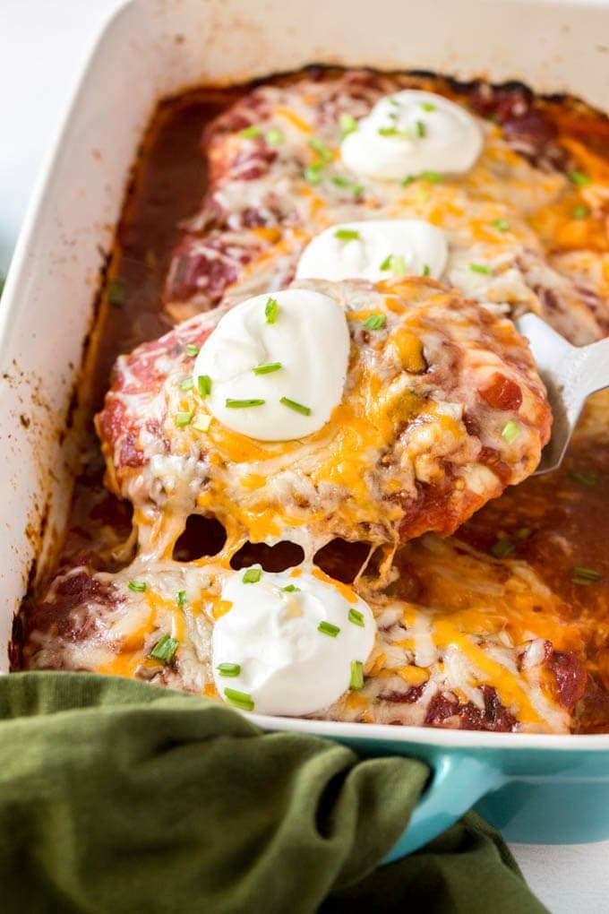 salsa chicken in a large dish, a spatula is holding up one breast