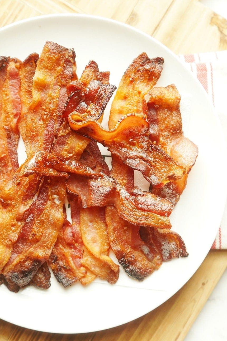 strips of crispy bacon from the oven sitting on a white plate.