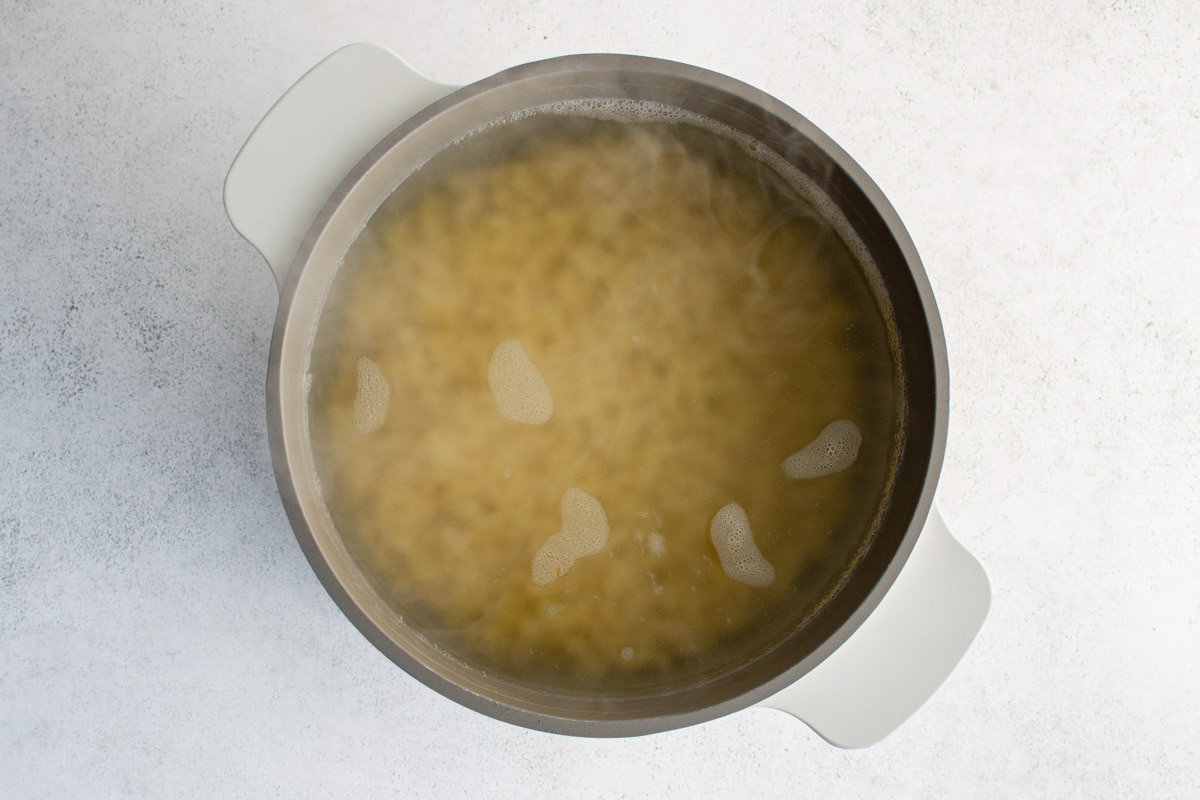 Macaroni noodles in a pot of water.
