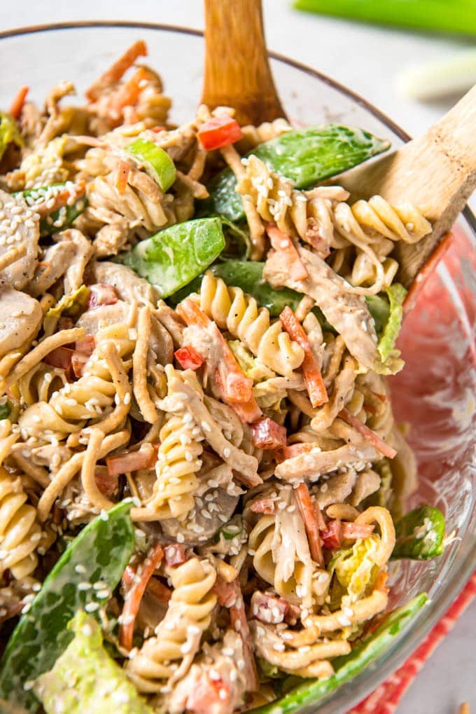 Chinese Chicken Pasta Salad in a large glass bowl with wooden spoons