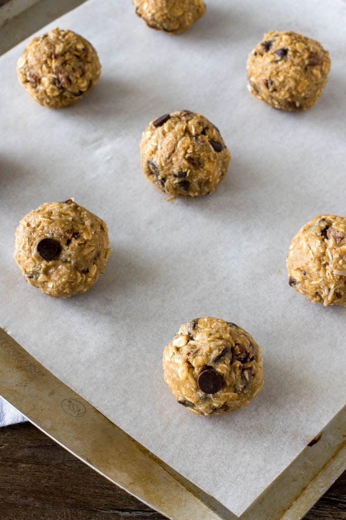 Cookie dough balls for cowboy cookies on a lined cookie sheet before being baked. 