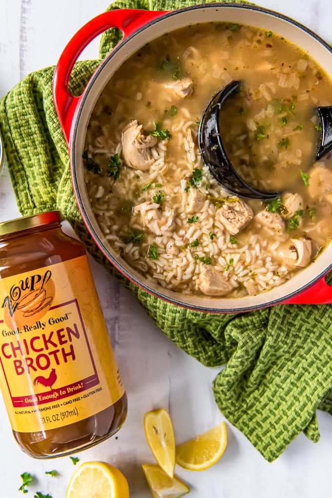 A pot of chicken and rice soup with a jar of Zoup chicken broth next to it