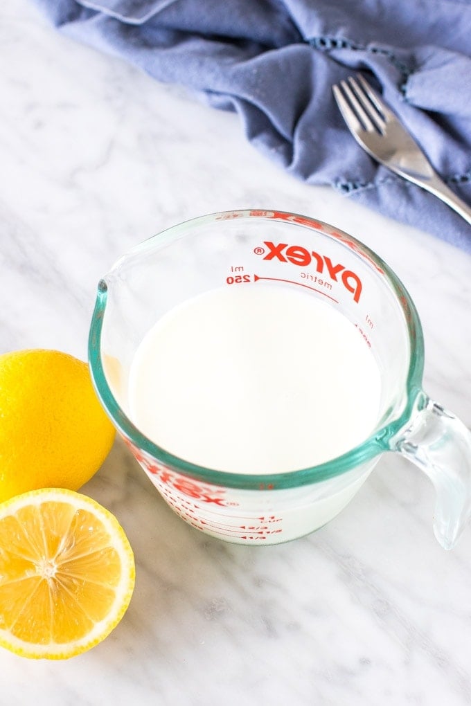 A cup of milk with 2 lemons for making buttermilk
