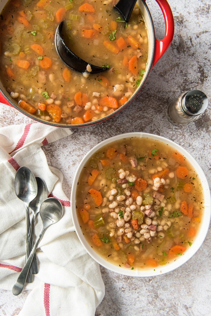 a bowl and a soup pot filled with navy bean soup and ham