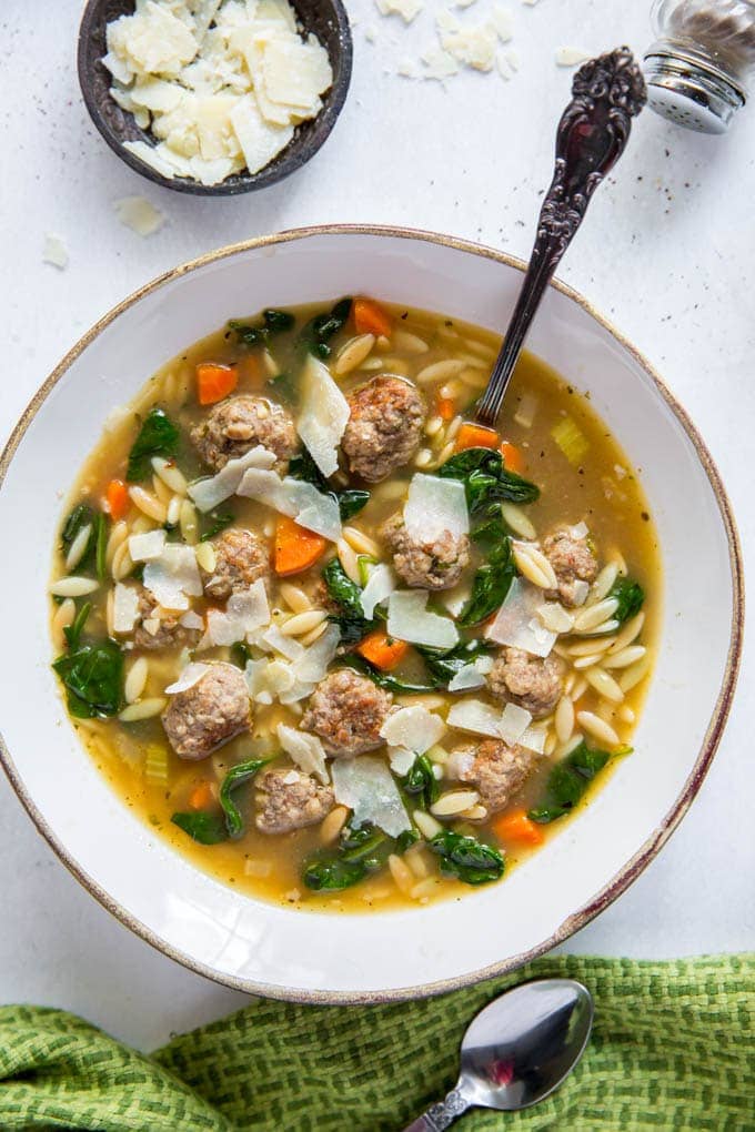 Bowl full of Italian Wedding Soup with Parmesan cheese on top.