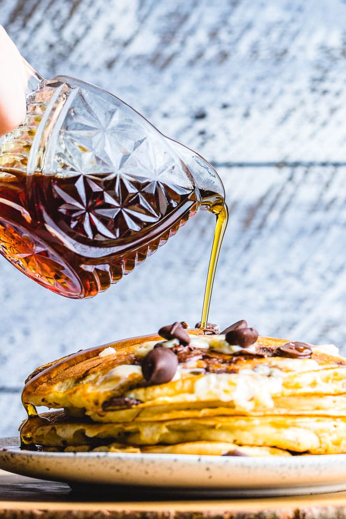 Syrup pouring onto plate of pancakes.