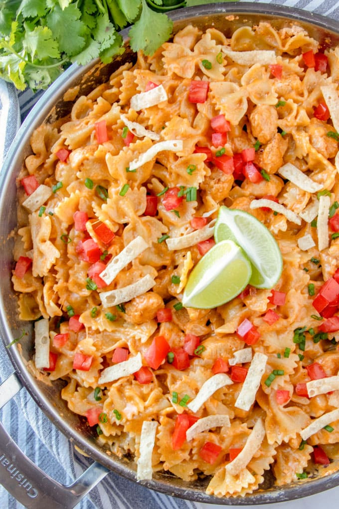 an overhead shot of chicken taco pasta with tortilla strips and limes