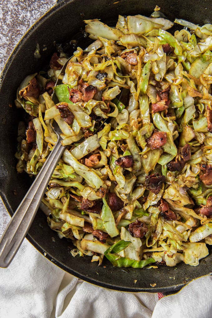 a cast iron skillet with fried cabbage and bacon