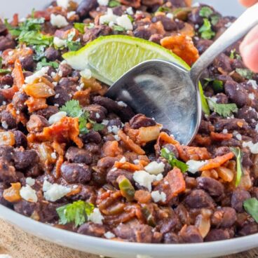 A bowl filled with Black Beans with wedge of lime