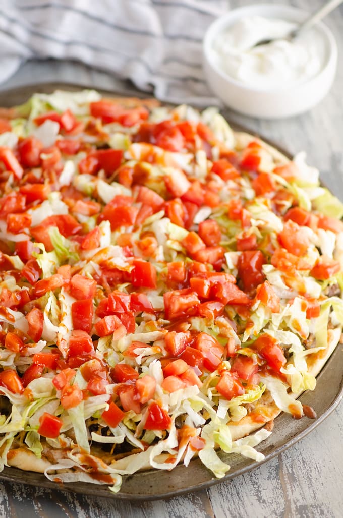 Taco Pizza with lettuce and tomatoes on top.