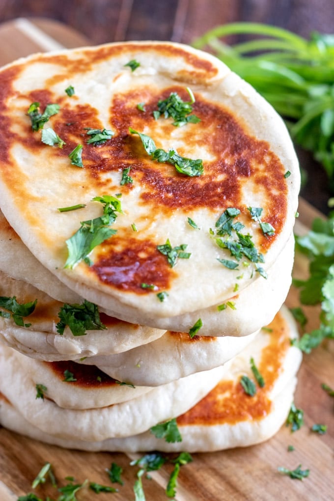 stacked naan brad with cilantro on a wooden board