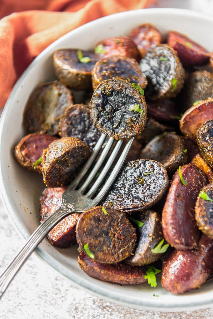 a bowl of purple potatoes with a fork stuck in one piece