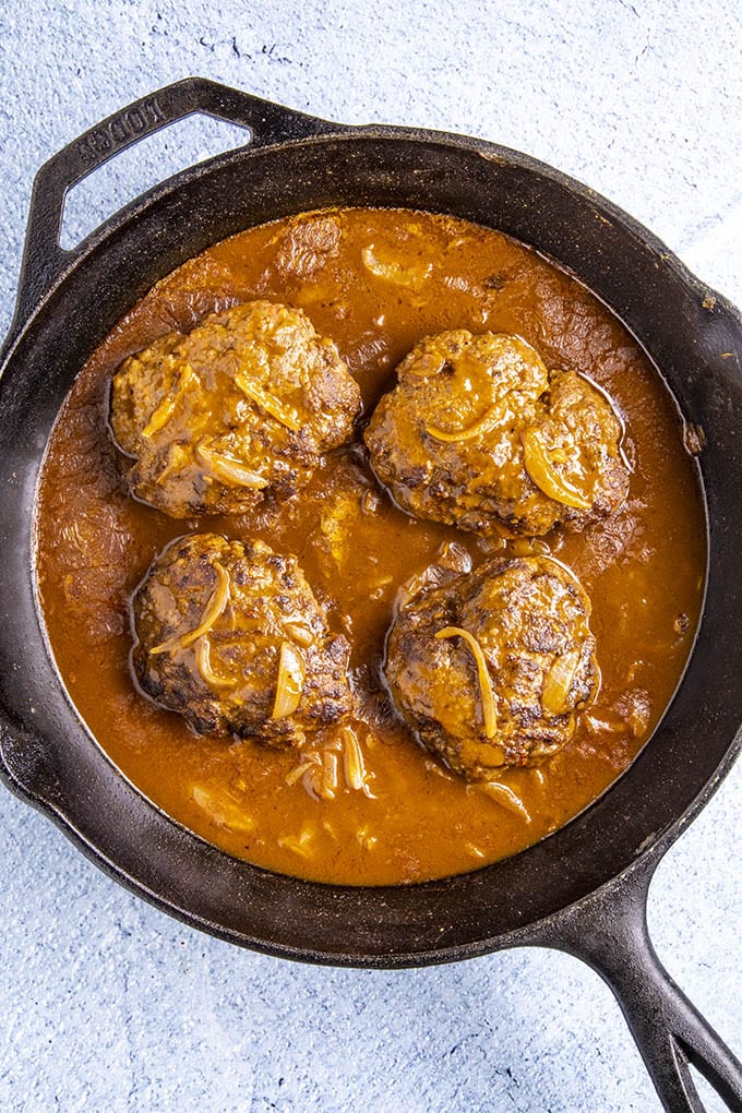 Hamburger Steaks simmering in a pan with lots of gravy