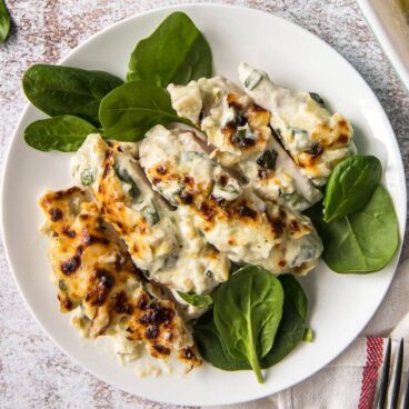 A plate of spinach artichoke chicken with spinach