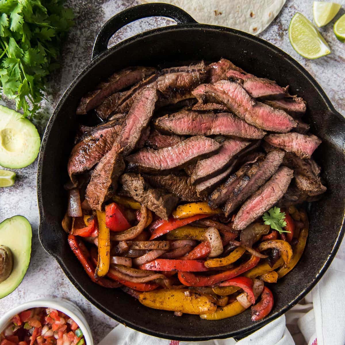 A cast iron skillet with Steak Fajitas