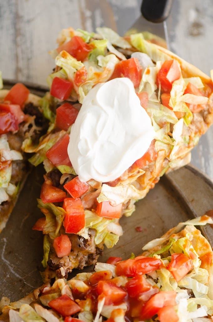 Slice of taco pizza with sour cream