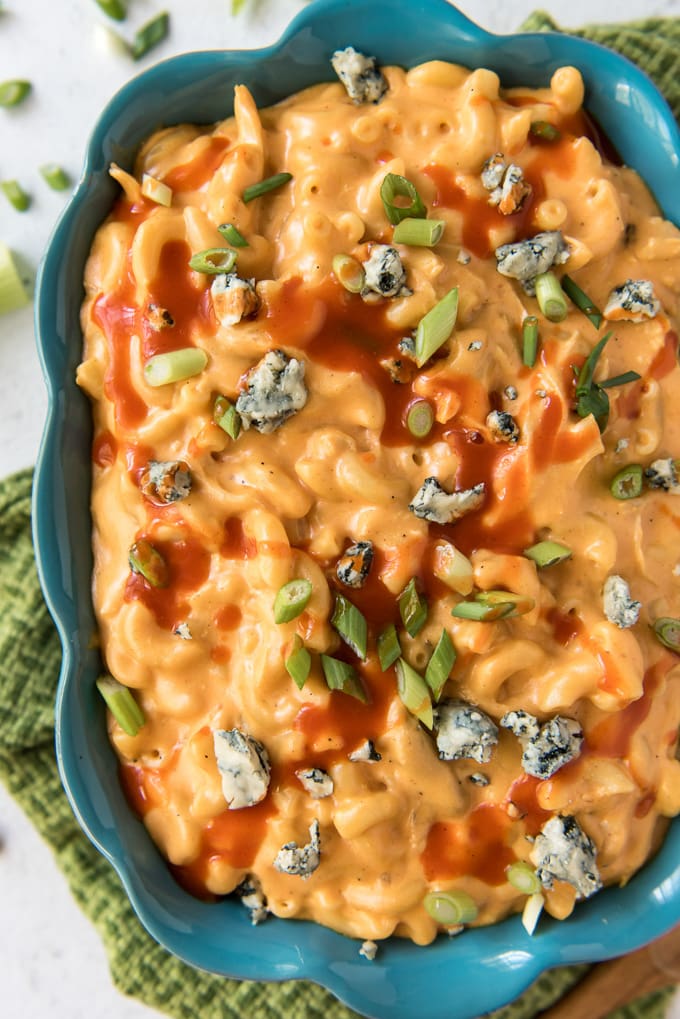 a blue ceramic dish with macaroni and cheese with chicken, buffalo sauce drizzle and blue cheese