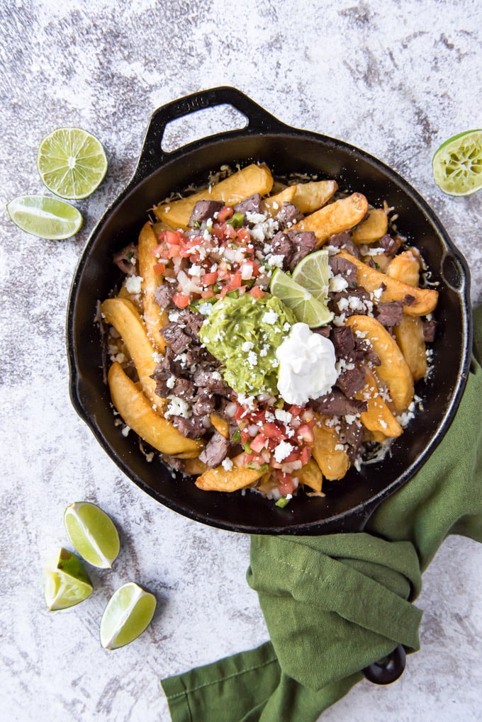 an overhead image of carne asada topped fires in a large skillet