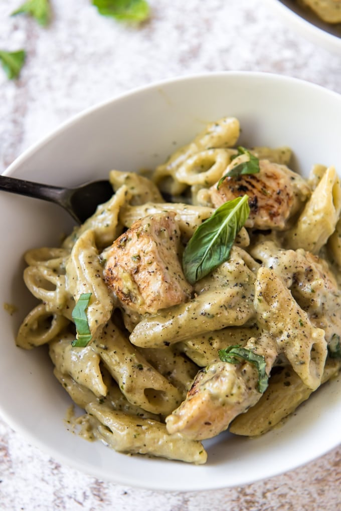 a white bowl with chicken pesto pasta in a creamy pesto sauce