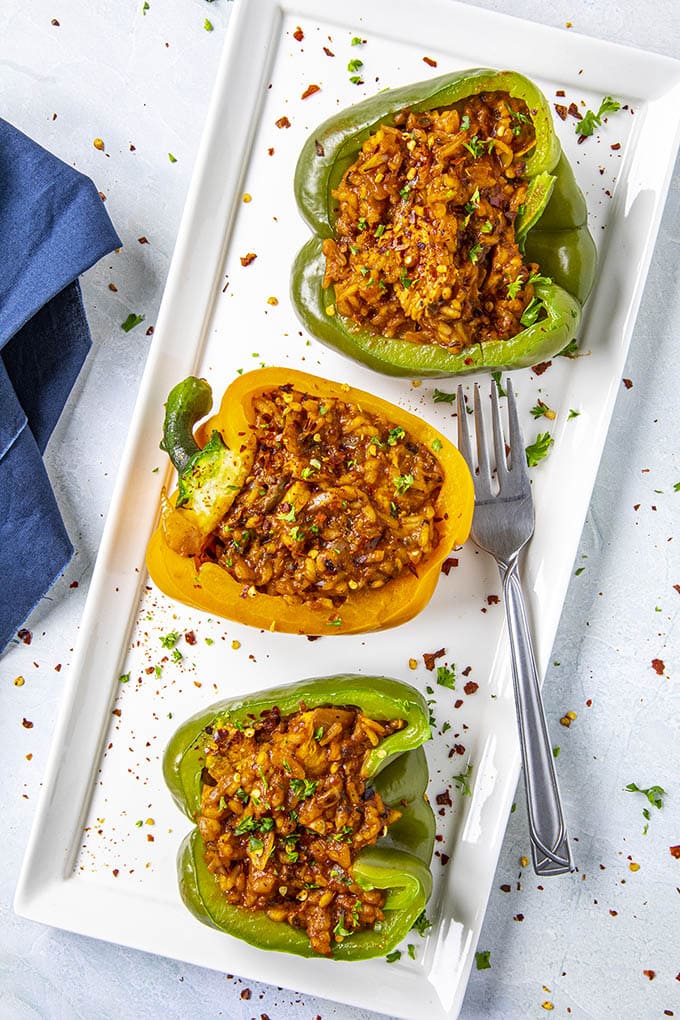 Three stuffed peppers with rice and chicken on a white platterready to serve