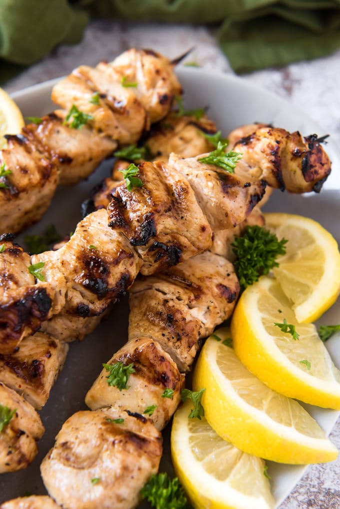 Juicy grilled chicken kabobs on a plate with slices of lemon