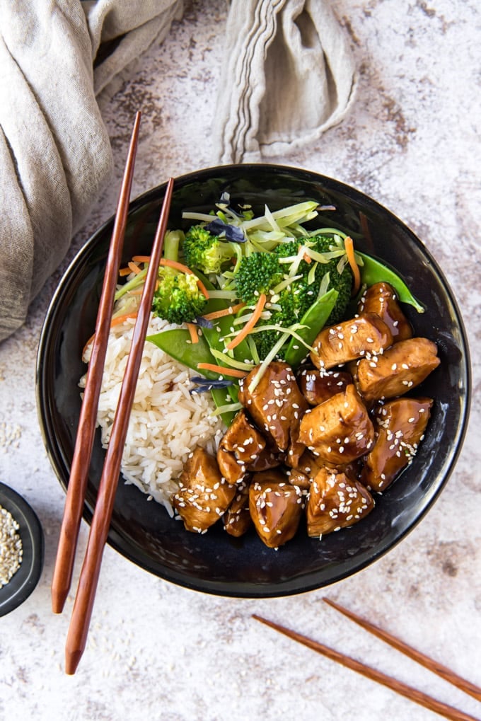 Teriyaki chicken with rice and veggies in a black bowl