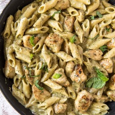 A pan filled with Chicken and Pasta, topped with a creamy pesto sauce.