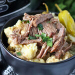 black bowl of mississippi pot roast on top of mashed potatoes