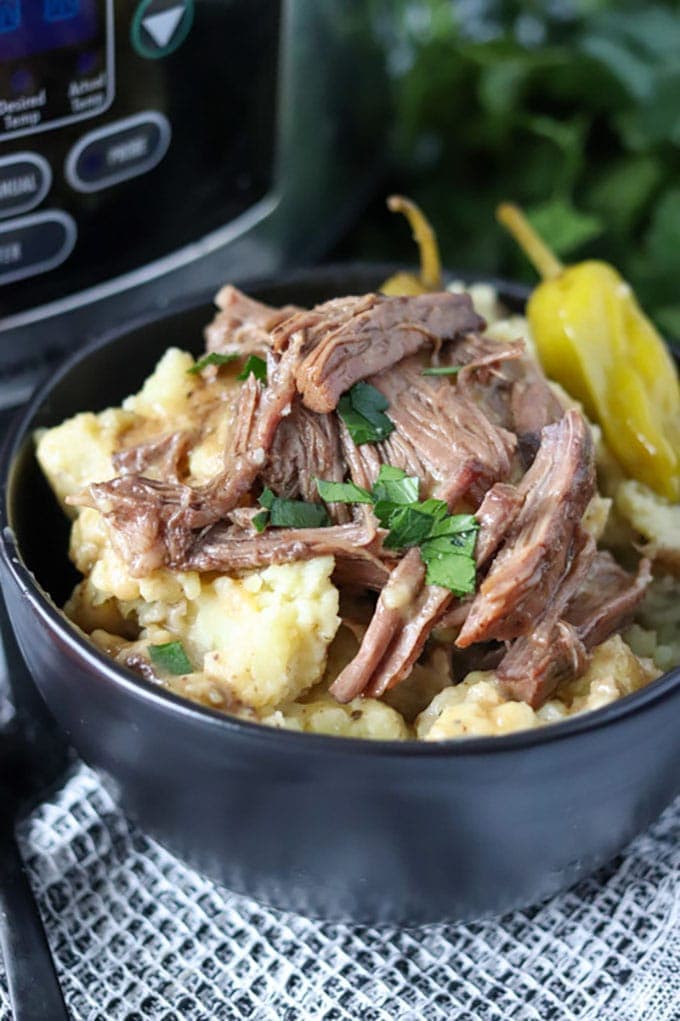 black bowl of mississippi pot roast on top of mashed potatoes