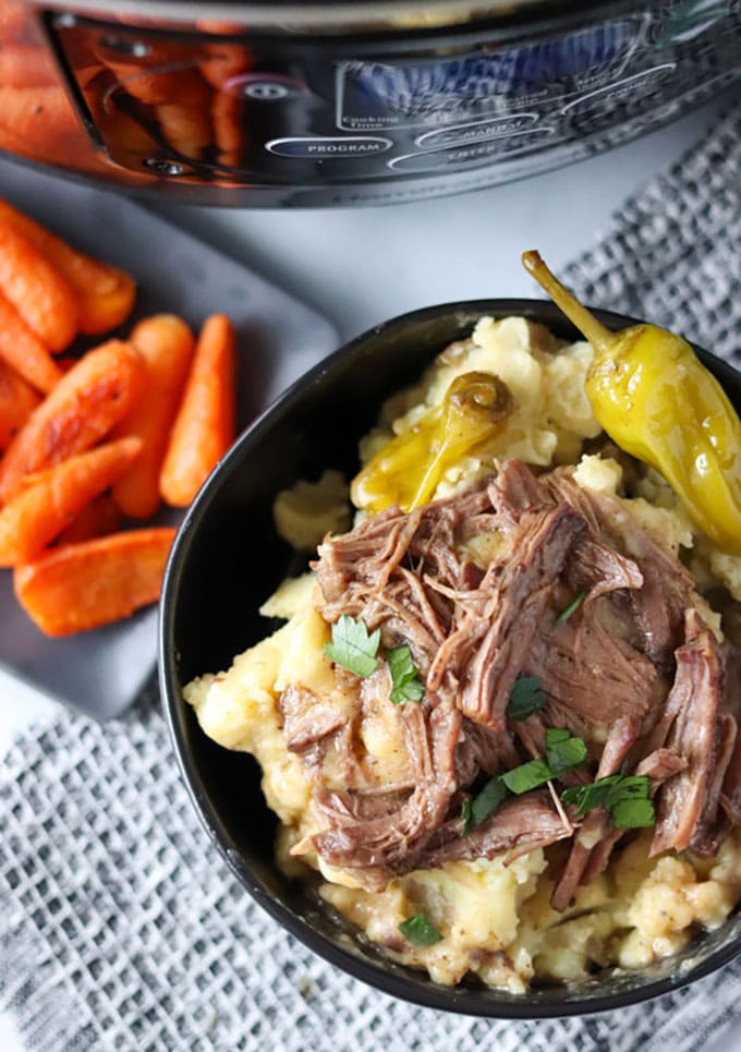 bowl of pot roast over mashed potatoes with side of carrots