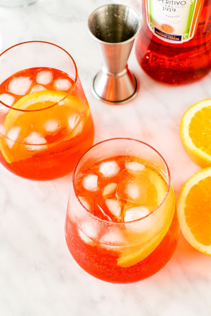 2 aperol spritz cocktails with ice and orange slices. 