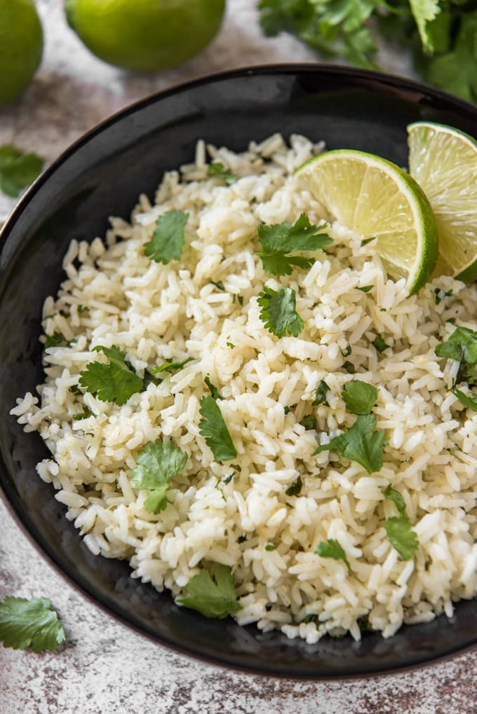 a bowl of rice with cilantro and limes