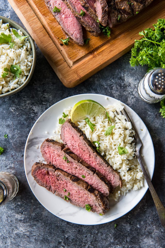 a small plate with sliced steak and rice on it.