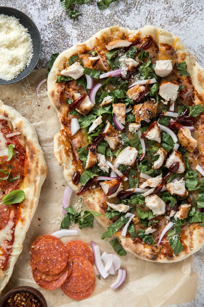 a grilled pizza crust with cheese, onions, chicken and basil. Sits on a whitewashed background