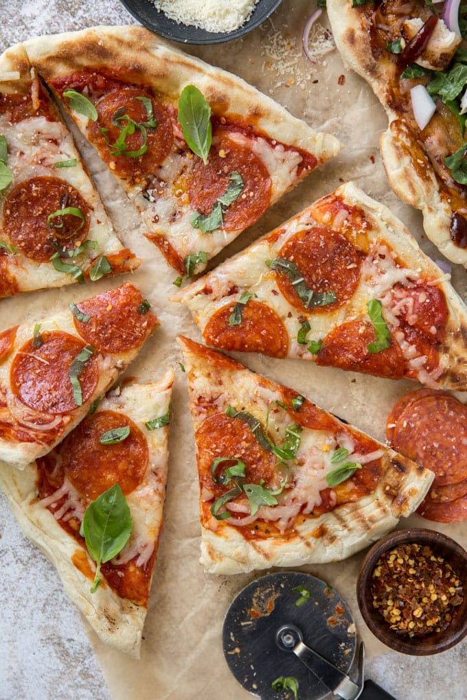 a grilled pizza with cheese and pepperoni, sliced, on a parchment paper.