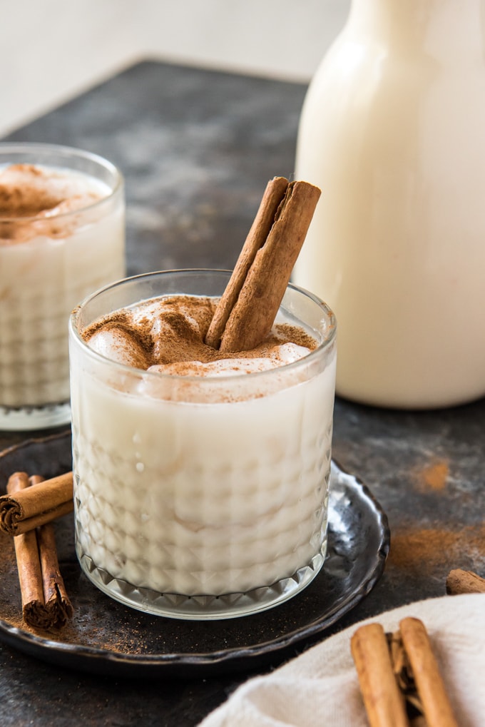 a glass of horchata over ice with a cinnamon stick.