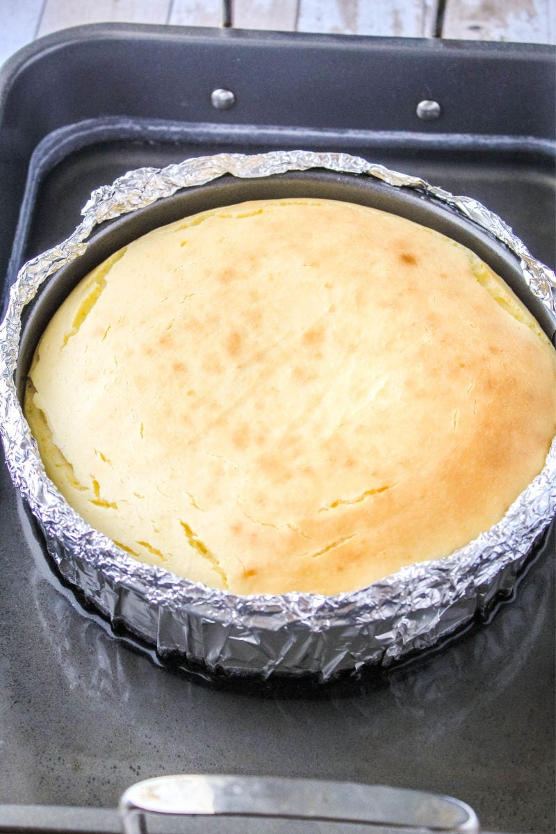 cheesecake right after baking in a foil wrapped springform pan in a roasting pan filled with water