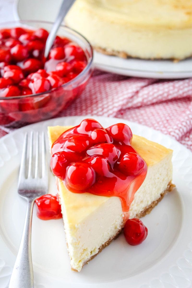 slice of new york cheesecake topped with cherry pie filling