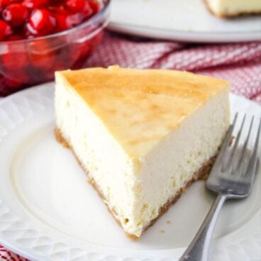 slice of new york cheesecake on a dessert plate with a fork