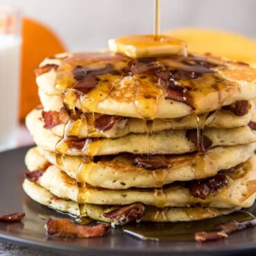 A plate of Bacon Pancakes topped with butter and syrup.