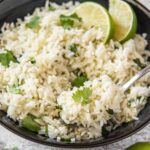 A plate of white rice with cilantro and lime
