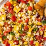A dish full of corn salad with tomatoes