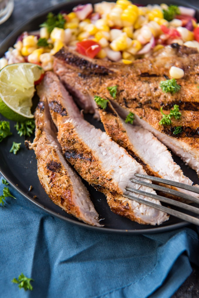 Sliced pork chop with a side of corn salad.