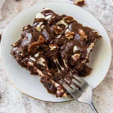 Slice of fudgy chocolate cake with marshmallows on a plate.