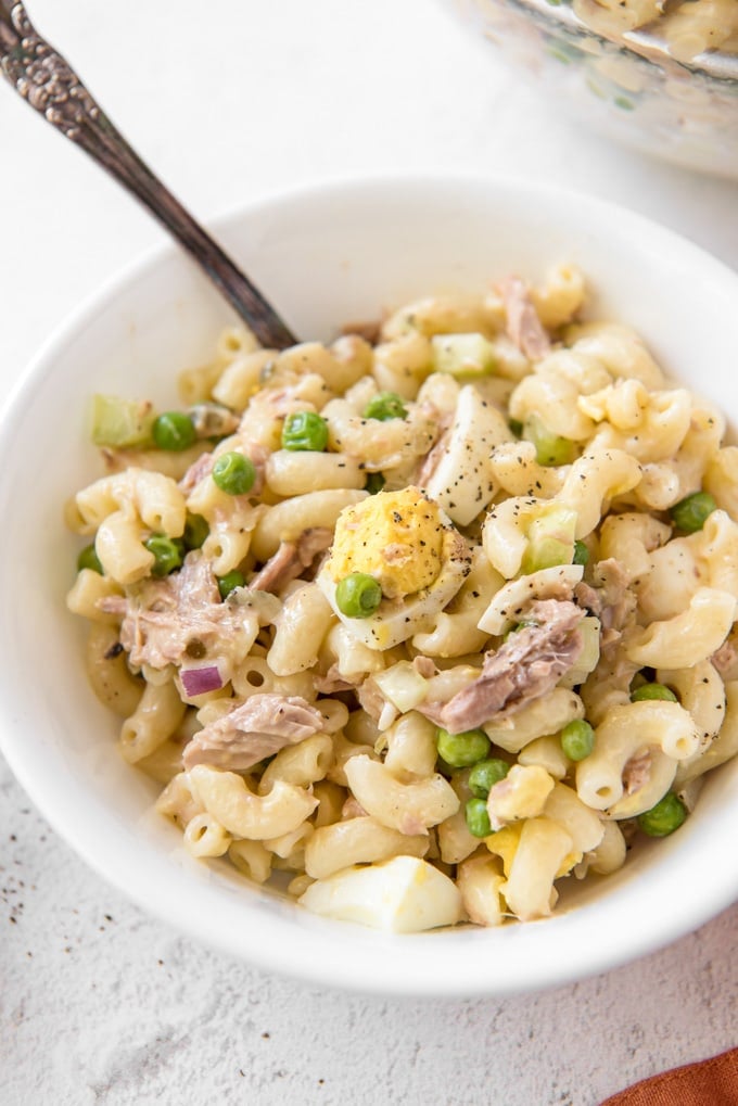A white bowl with tuna macaroni salad and a fork in the bowl.