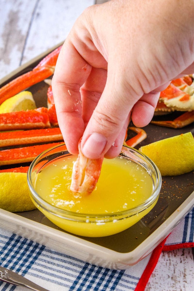 Making crab legs is easier than you think! Ready in only 5 minutes, these crab legs are the best way to treat yourself to a fancy meal at home! piece of crab meat being dipped into melted butter
