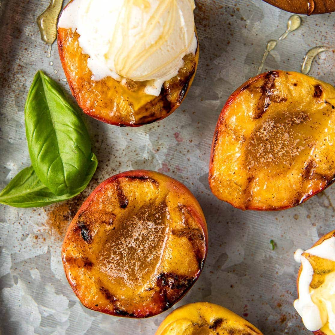 A close up of grilled peaches with vanilla ice cream.