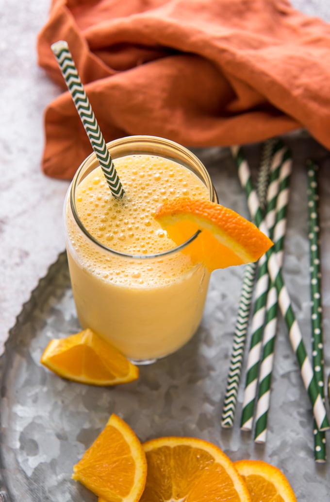Orange smoothie in a glass with slices of fresh oranges.