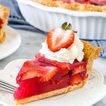 Slice of strawberry pie with whipped cream and a strawberry on top.