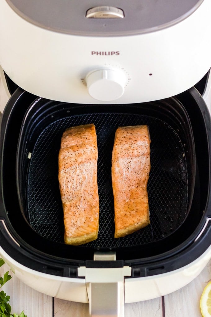 Two salmon filets being cooked in an air fryer.